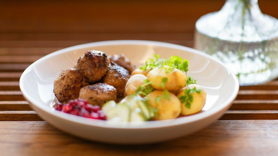 En tallrik med köttbullar, potatis, lingon pressgurka.